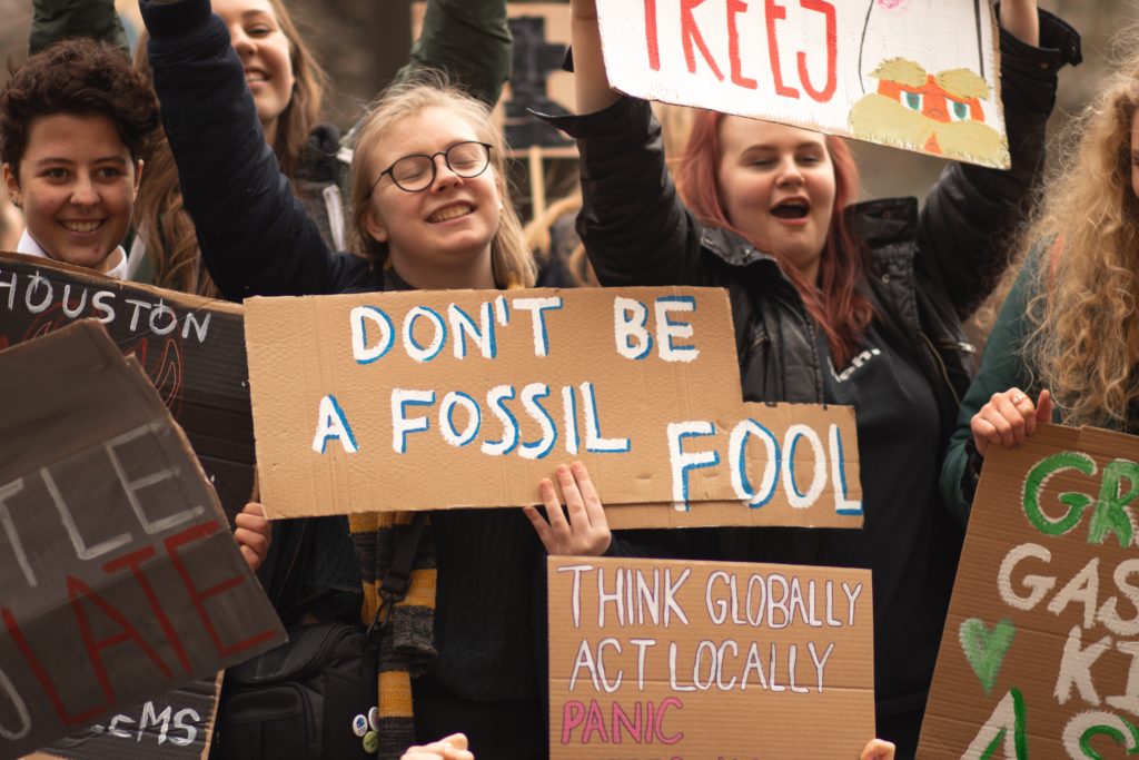 Image showing crowd protesting with banner reading 'Don't be a fossil fuel' for article about motorsport website digital sustainability