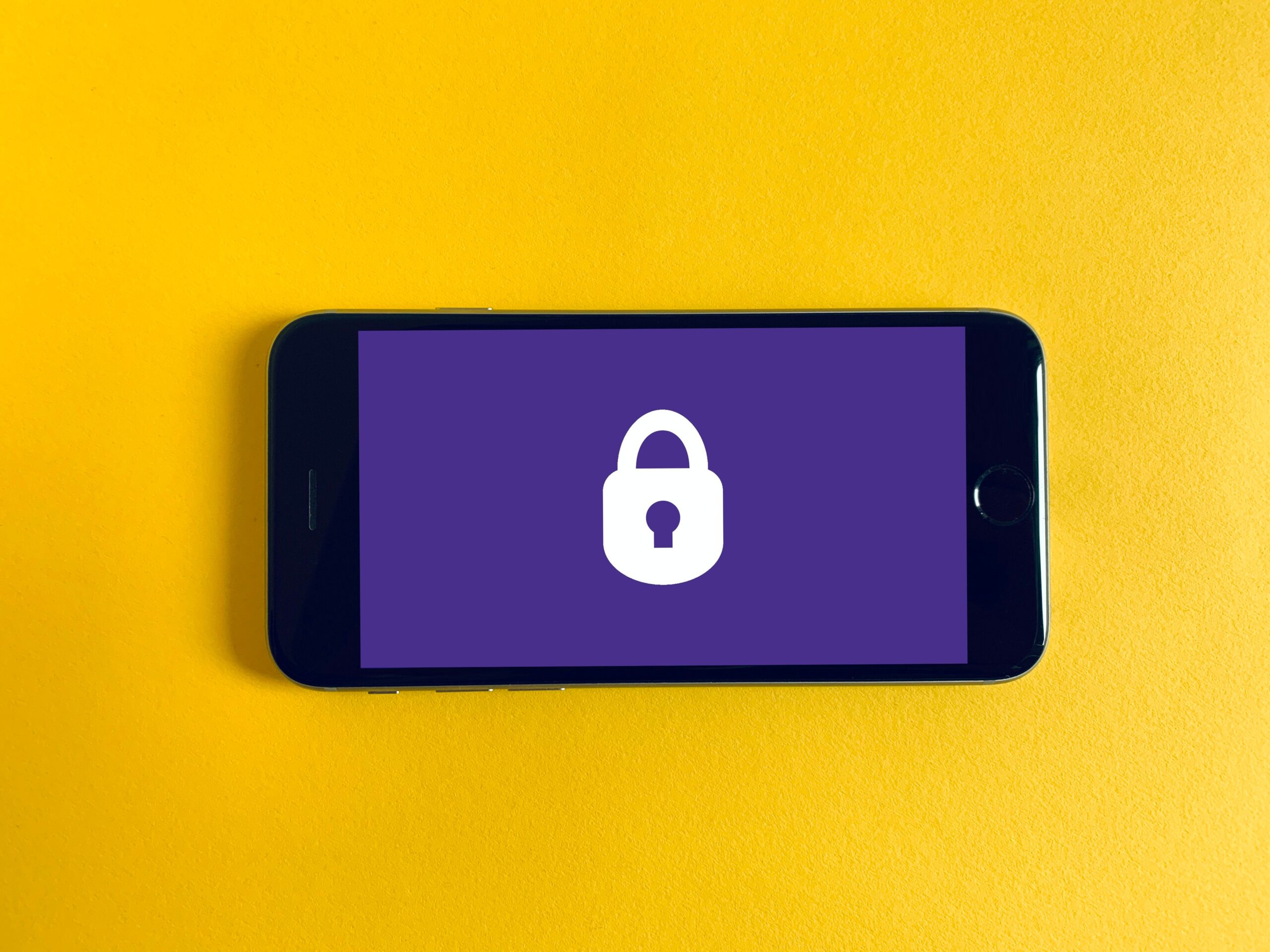 Image showing an iphone screen that shows a purple image and white padlock. The iphone sits on a yellow background. Image used to illustrate content about the security of an online donation facility.