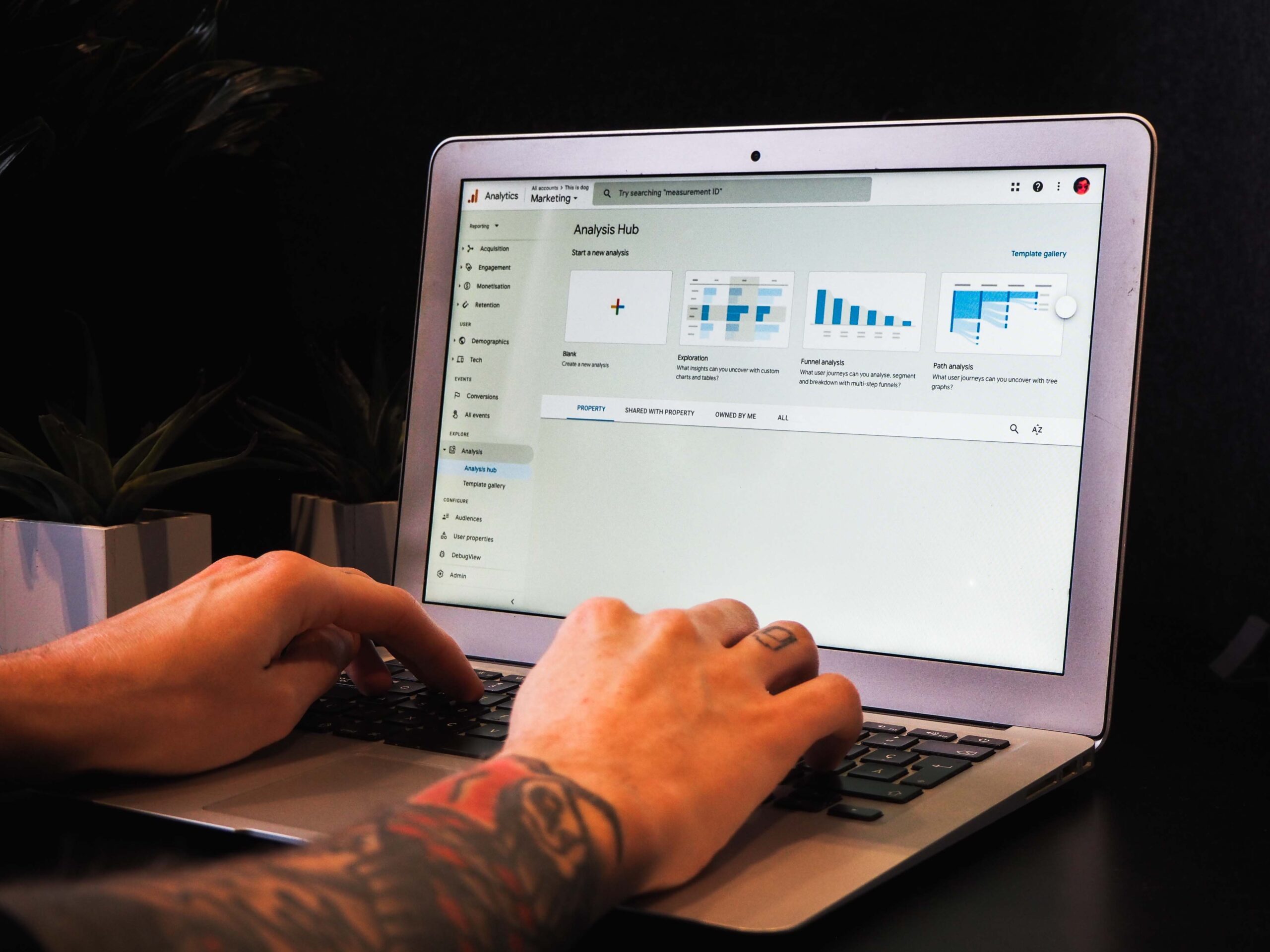 Image showing someone from a data driven business typing on a macbook with the Google Analytics 4 interface visible on screen.